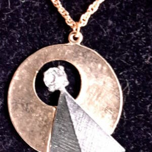 Gold chain with a pyramid and circle pendant.