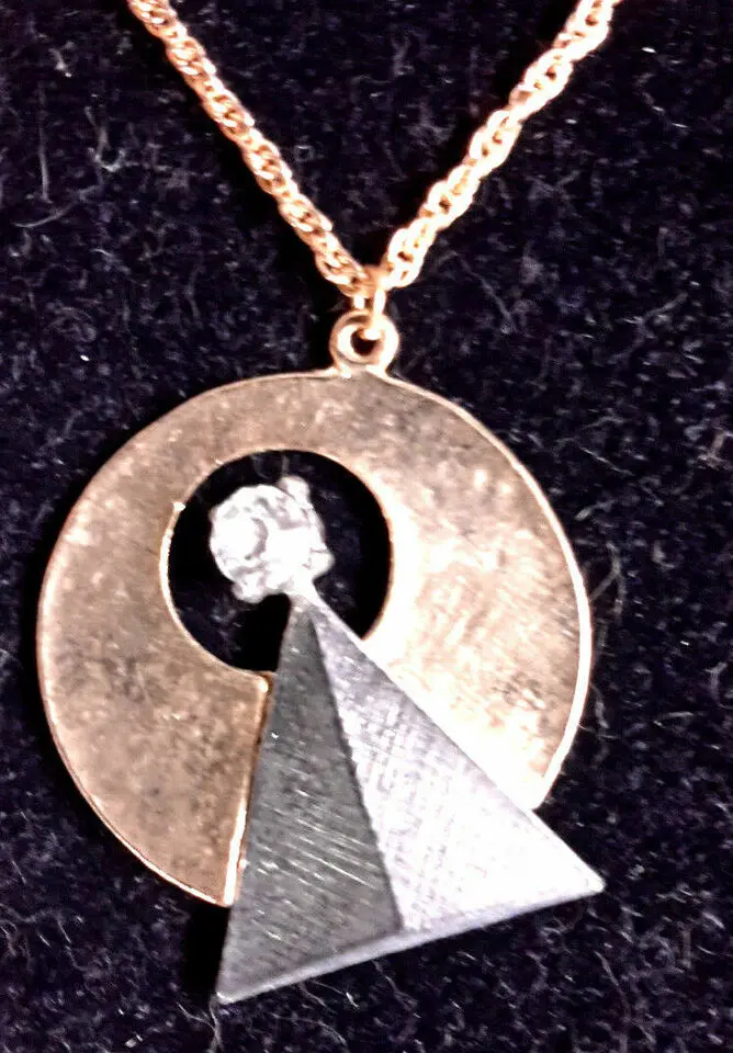 Gold chain with a pyramid and circle pendant.