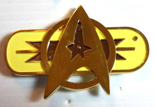 Gold Starfleet command pin with yellow stripe.