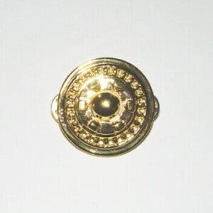 Gold round button with ornate design.