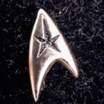 Silver Starfleet insignia pin on black fabric.