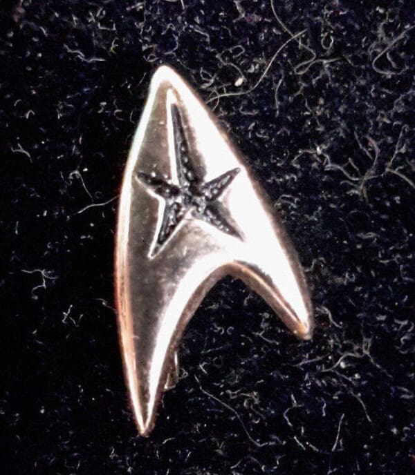 Silver Starfleet insignia pin on black fabric.