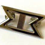 Silver pin with double chevron design.