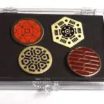 Four circular pins with geometric designs in a box.