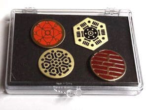 Four circular pins with geometric designs in a box.