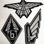 Three grey and black embroidered military patches.