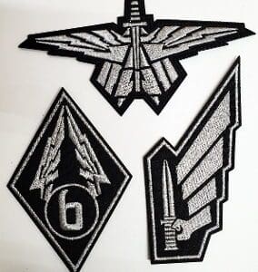 Three grey and black embroidered military patches.