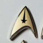 Gold and black Starfleet insignia pin.