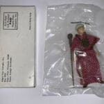 Red-robed figure with a staff in a plastic bag.