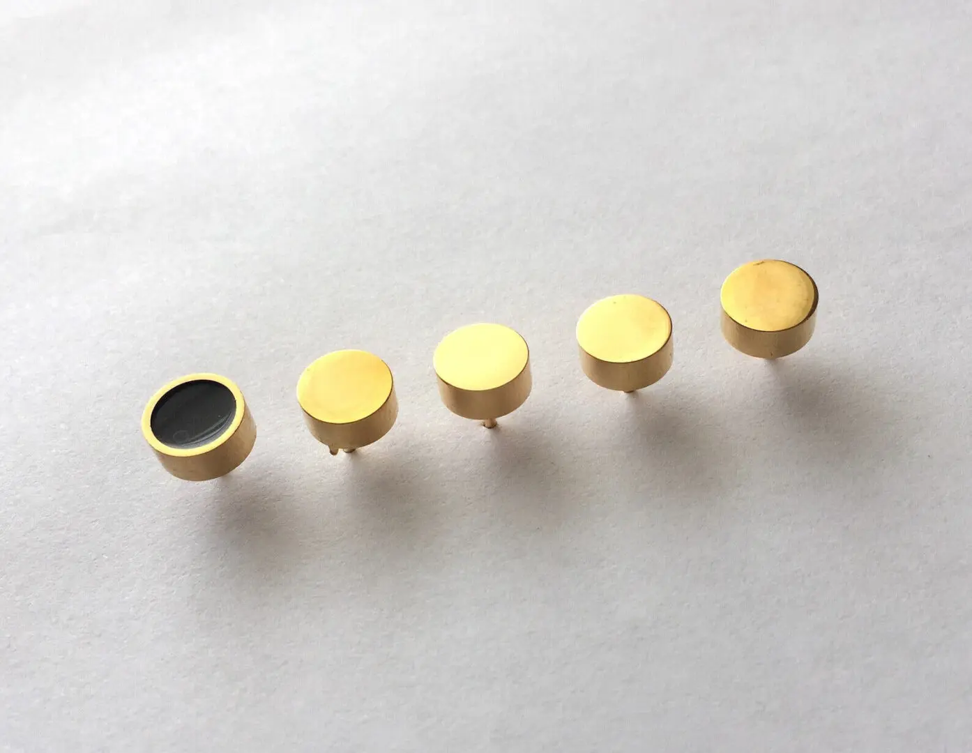 Five gold round buttons, one black.