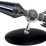 Grey and blue spaceship figurine on stand.