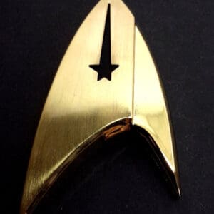 Gold Star Trek insignia on black background.