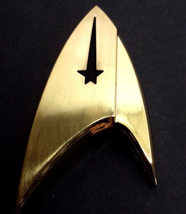 Gold Star Trek insignia on black background.