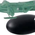 Green spaceship model on a black stand.